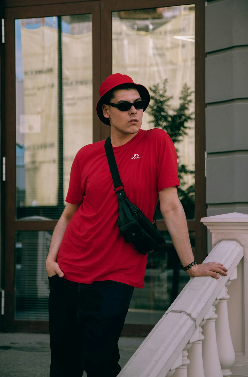 man in red crew neck t-shirt and black pants wearing black sunglasses