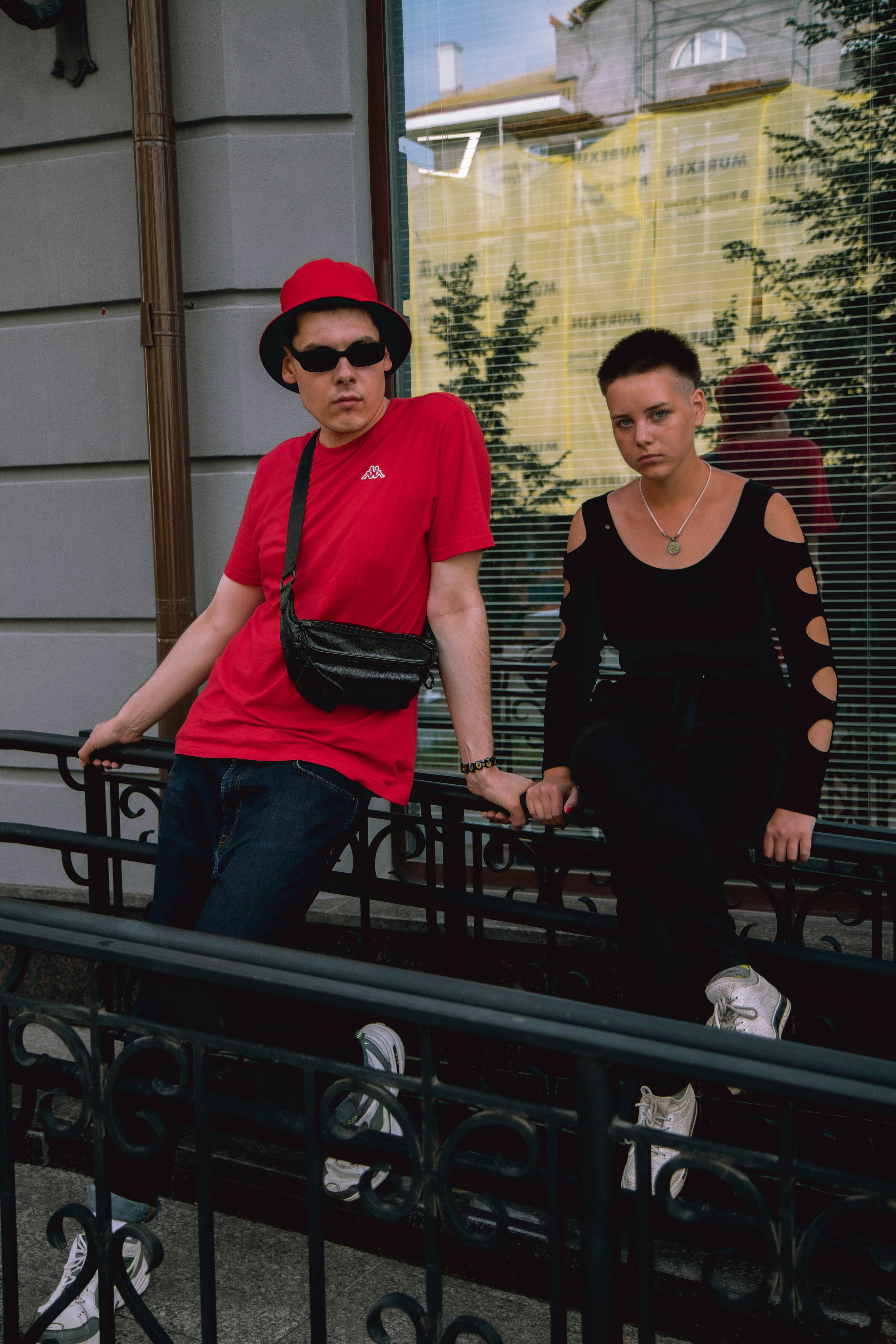 man in red crew neck t-shirt and blue denim jeans standing beside woman in black