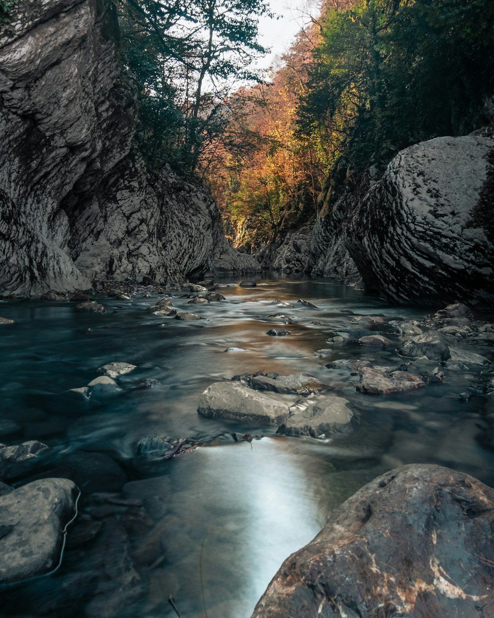 body of water between gray rock formation during daytime