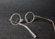 Close-up of stylish round eyeglasses with thin metal frames resting on a white surface.