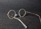 Close-up of stylish round eyeglasses with thin metal frames resting on a white surface.