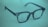 A pair of dark-rimmed eyeglasses rests on a soft, blurred green background. The glasses have a simple, classic design with a rectangular frame and clear lenses. The lighting casts a subtle shadow, adding depth to the image.