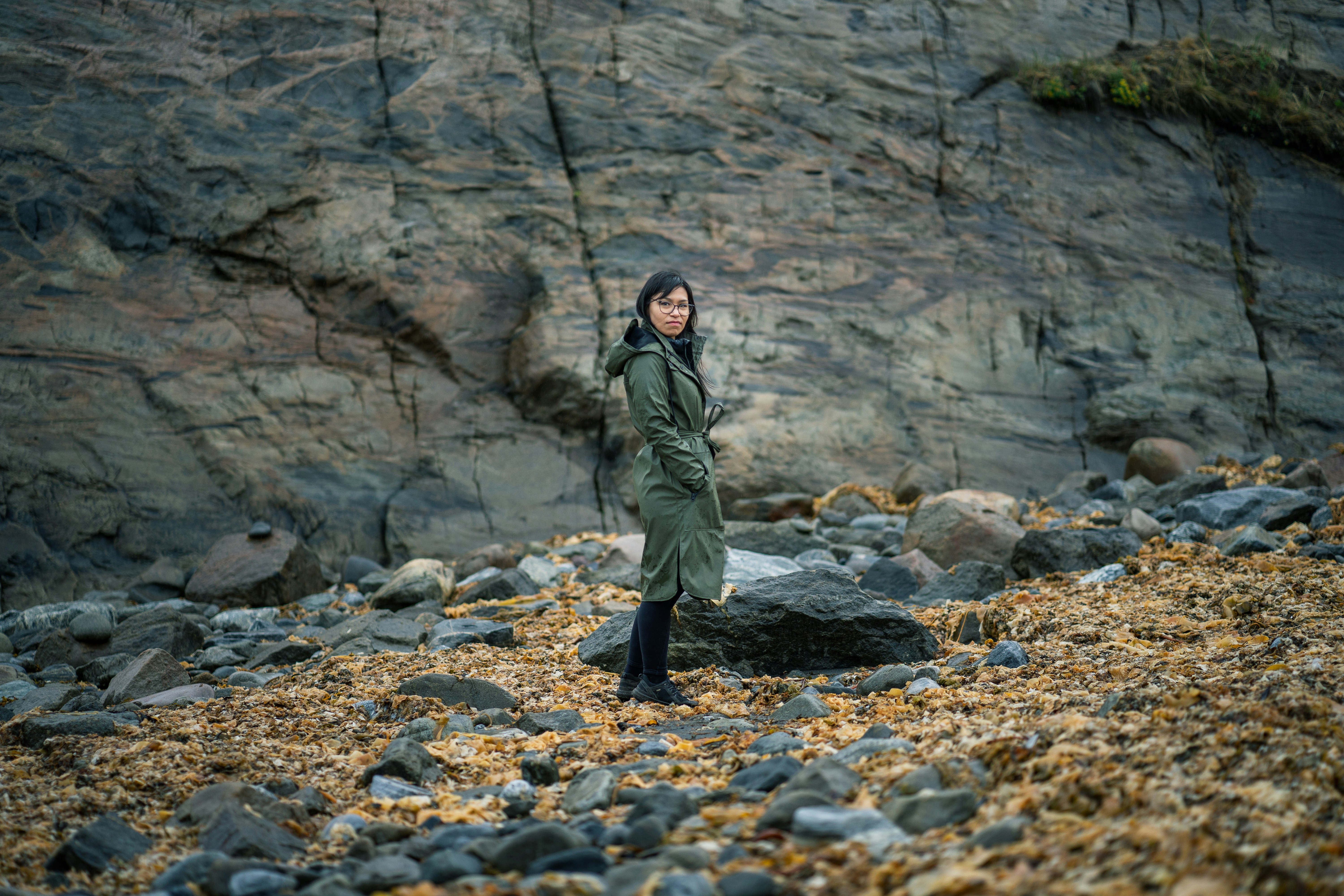 man in green jacket standing on rocky ground
