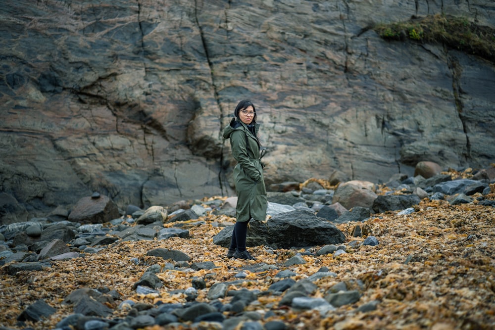 man in green jacket standing on rocky ground