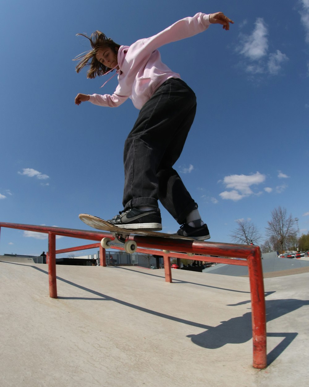 man in pink dress shirt and black pants jumping on brown wooden ladder during daytime