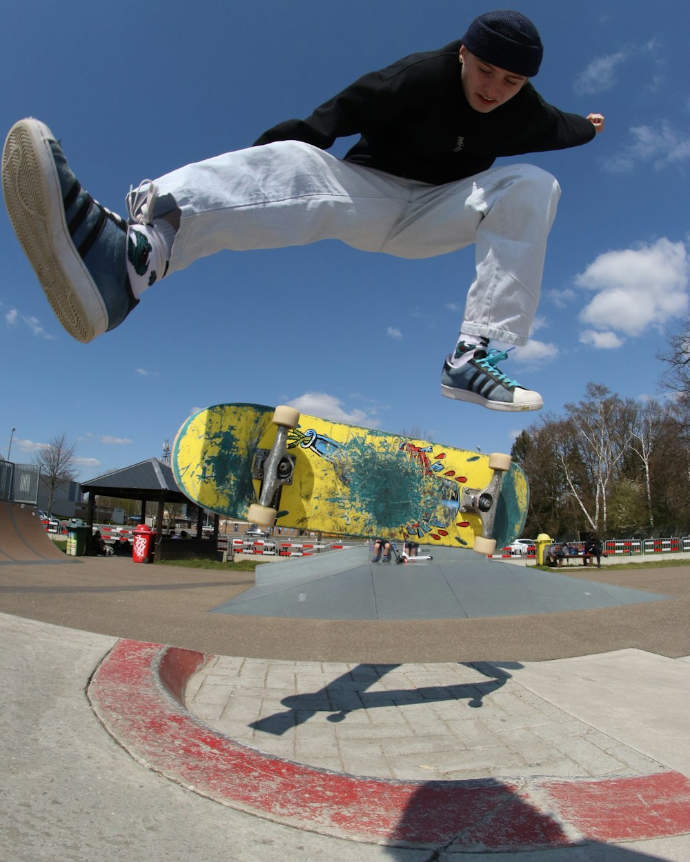 man in white pants and black jacket jumping on gray concrete floor during daytime