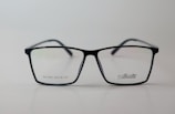 A pair of rectangular eyeglasses with a thin black frame, featuring the brand name 'Silhouette' on the right lens. The lenses are transparent, and small text is present on the left lens.