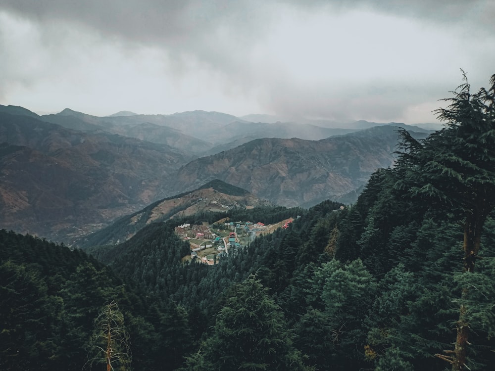 green trees on mountain under cloudy sky during daytime