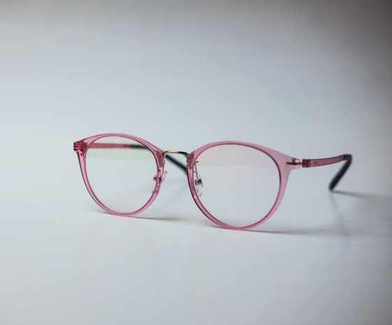 Close-up of stylish eyeglasses with magenta frames on a clean white background