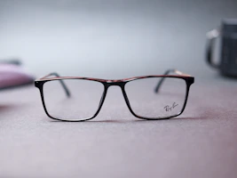 Branded eyewear with elegant frames showcased against a soft, neutral background.