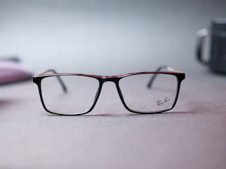 Minimalist display of white and gold Ray-Ban sunglasses on black velvet