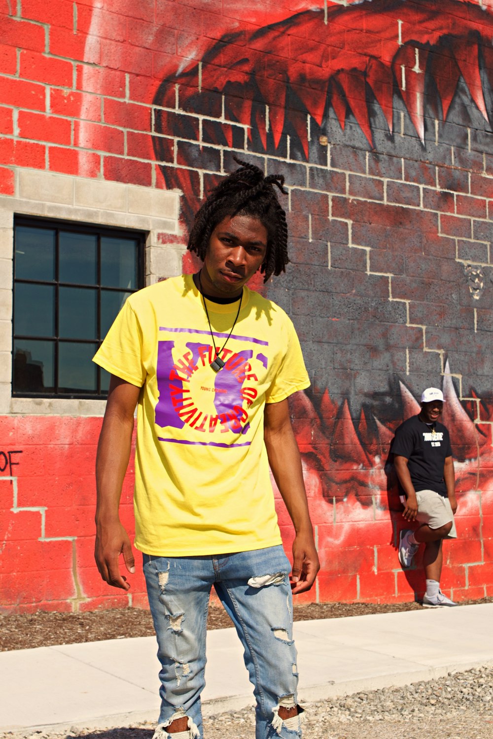 man in yellow crew neck t-shirt standing beside red brick wall