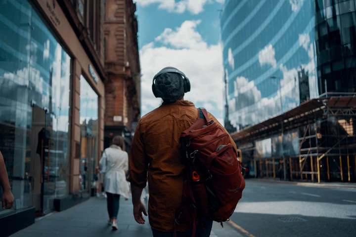 Man in an orange jacket walking down a street