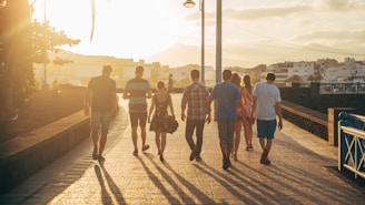 A small group walking along a scenic harbor trail with city skyline in the background during sunset.