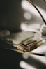 A textured, gold-toned massage tool with small spikes is placed on a reflective surface. In the background, there are smooth, white stones or crystals. The lighting creates soft, diffused shadows that add a serene and luxurious feel.