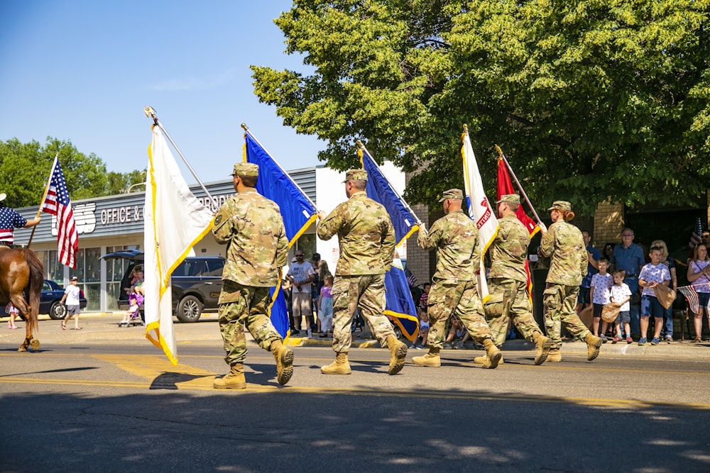 Soldats en uniforme de camouflage marron et vert debout sur la route pendant la journée