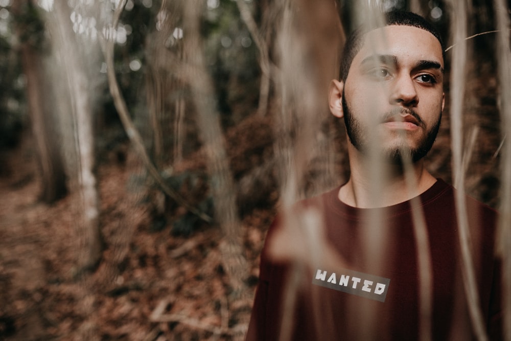 man in red crew neck shirt standing in forest during daytime