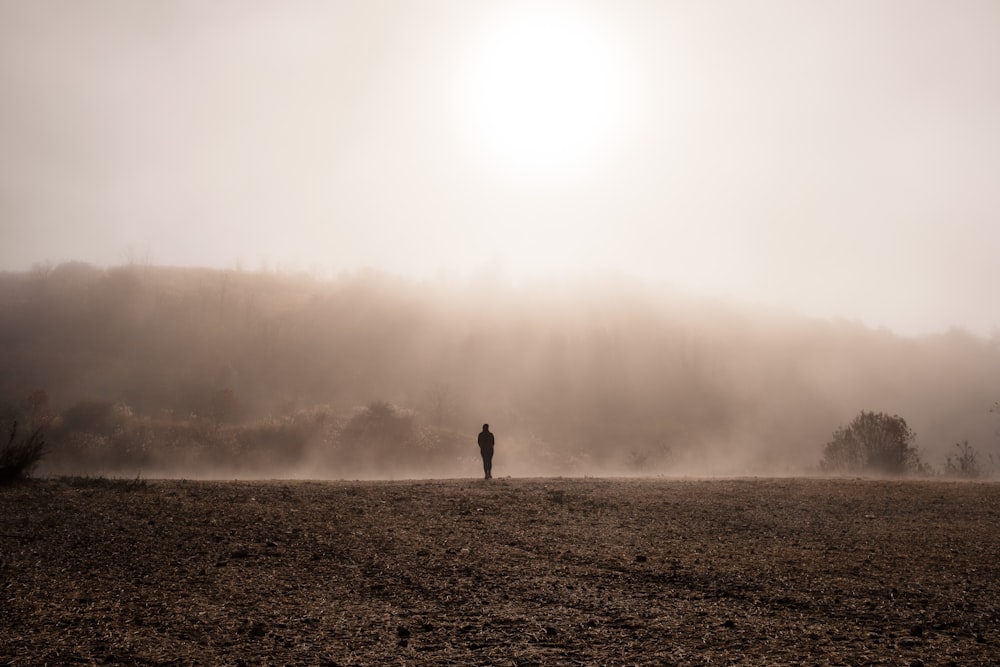 personne debout sur le sable gris par temps de brouillard