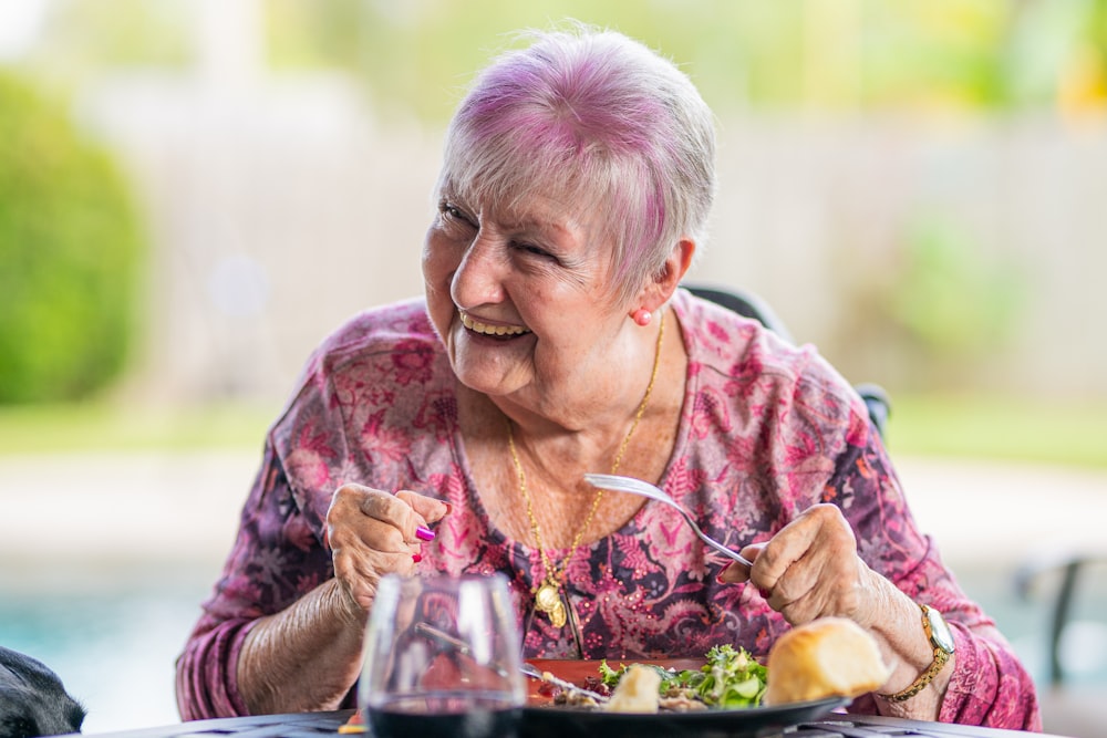 woman in purple and pink floral long sleeve shirt sitting on chair