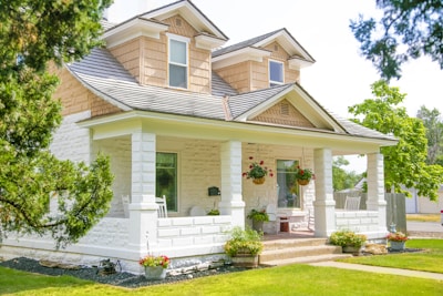 A charming two-story suburban house with a welcoming front porch and lush green lawn.