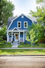 blue and white wooden house near green trees during daytime