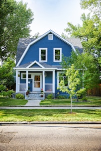 A charming two-story house with a neatly manicured lawn and Texas bluebonnets in bloom.