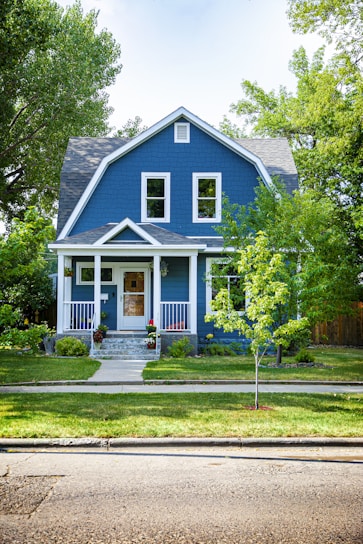 A charming two-story family home with a freshly painted blue exterior and a manicured front lawn.