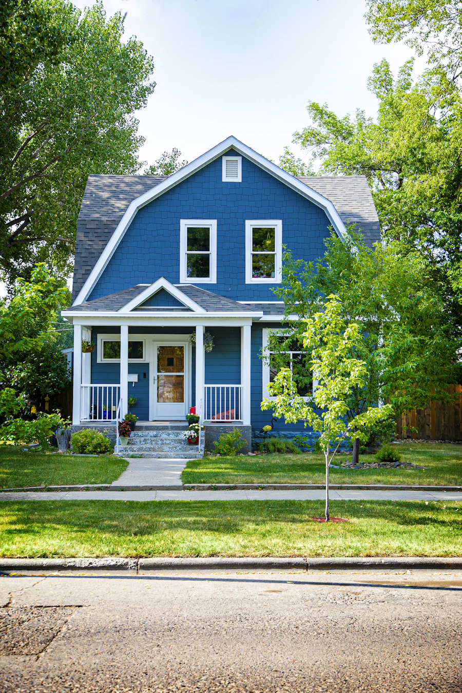 A blue house with a crisply mown front lawn and clean edges along the sidewalk.