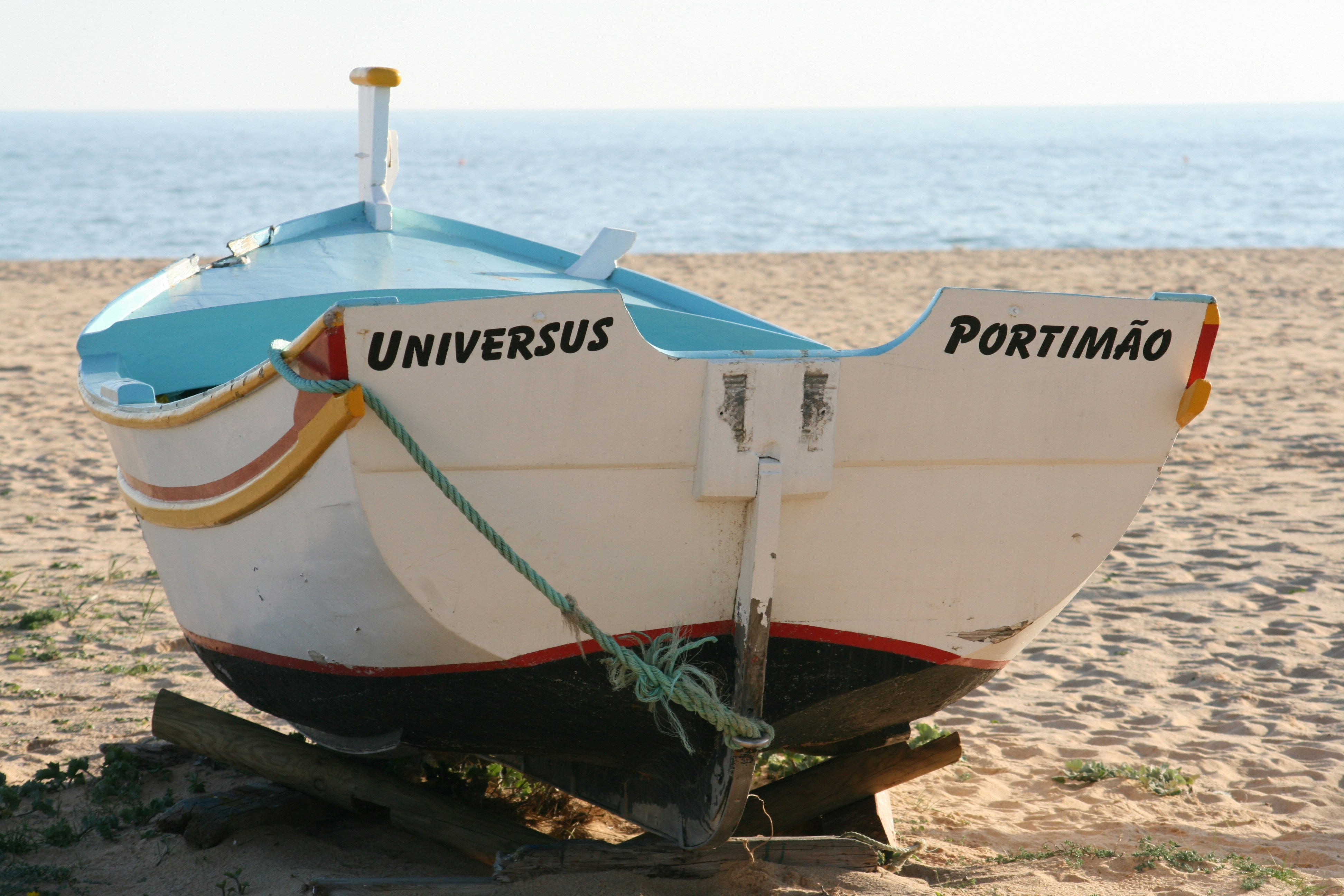 Weißes und rotes Boot am Strandufer tagsüber