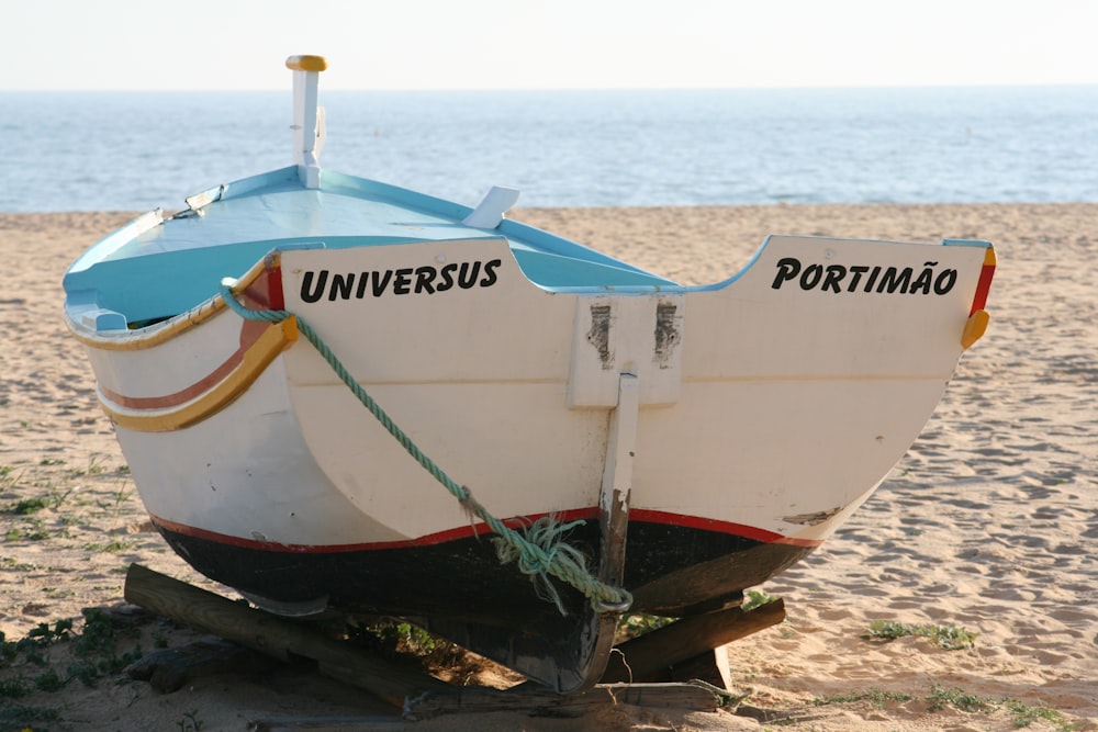 white and red boat on beach shore during daytime