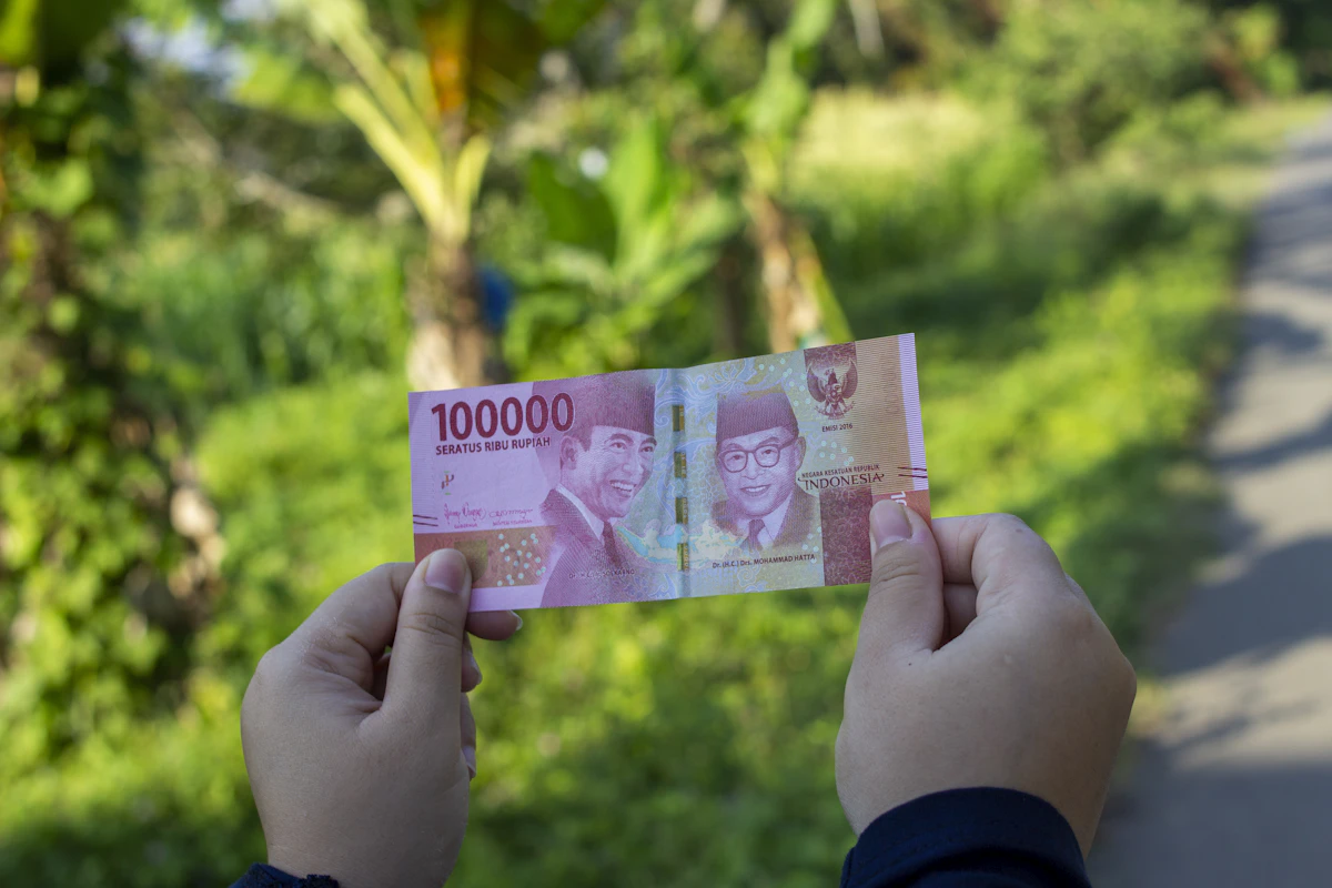 Seseorang memegang uang kertas rupiah sepuluh ribuan