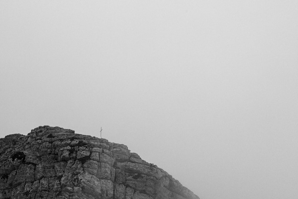 personne debout sur une formation rocheuse pendant la journée brumeuse