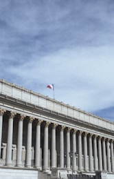 white concrete building with flags on top under blue sky during daytime
