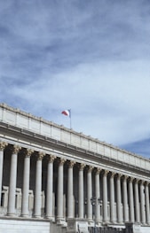 white concrete building with flags on top under blue sky during daytime