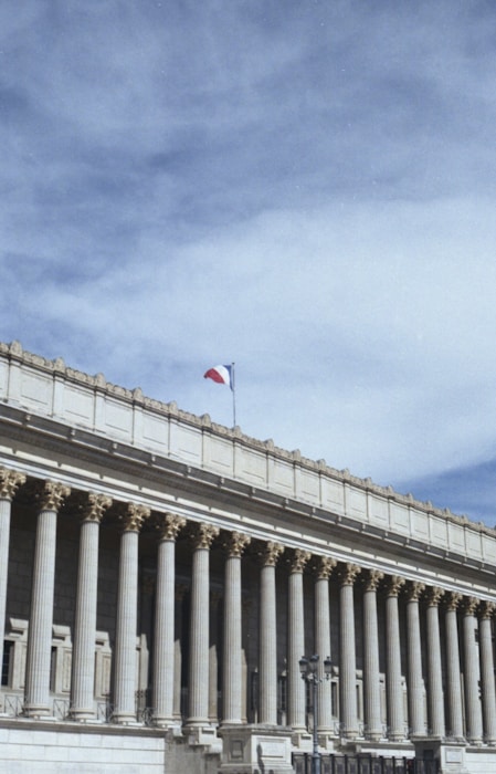 white concrete building with flags on top under blue sky during daytime