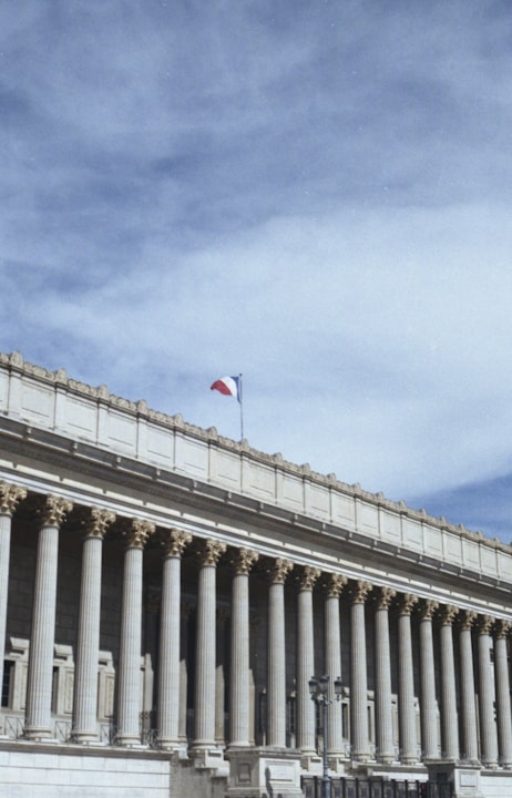 white concrete building with flags on top under blue sky during daytime