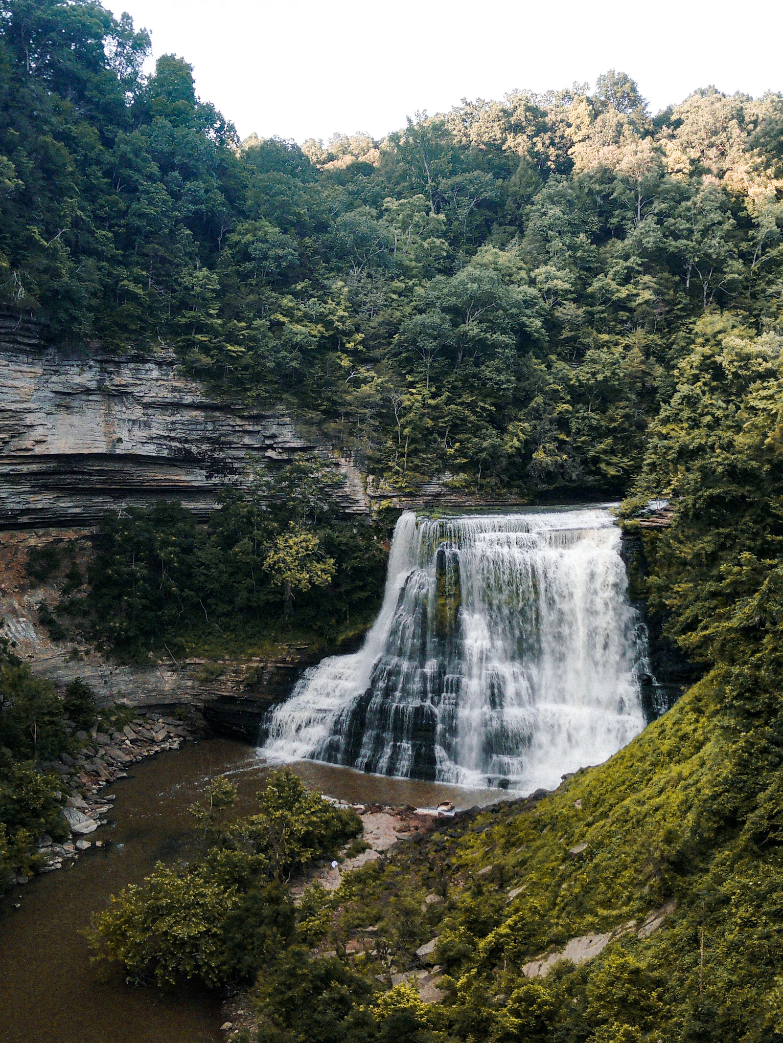 A waterfall dropping through green woods.