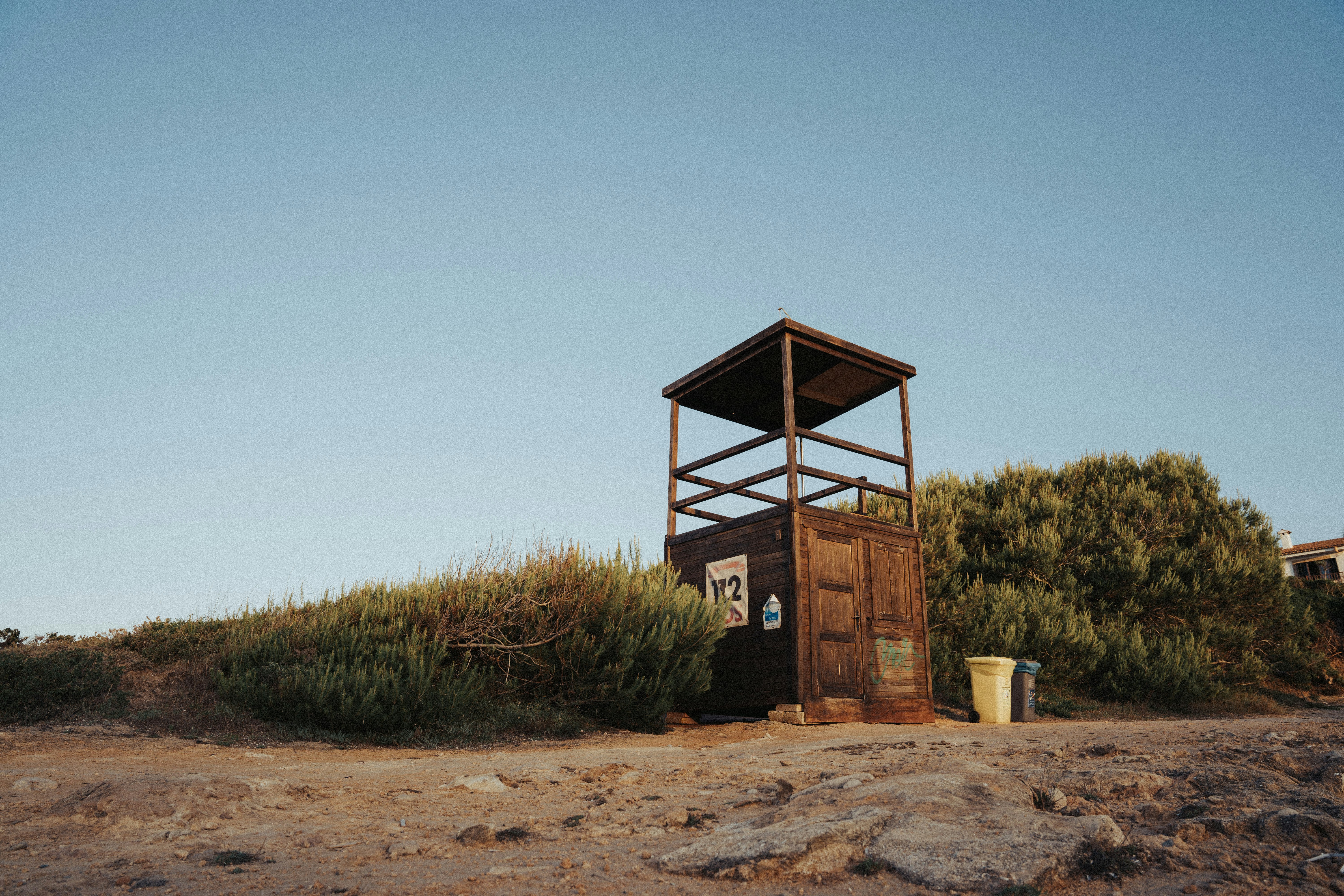 brown wooden lifeguard tower on brown sand during daytime