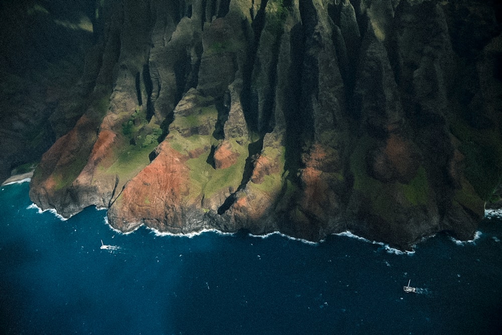 brown and green rock formation beside blue sea during daytime