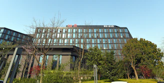 A sleek corporate office building surrounded by lush greenery.