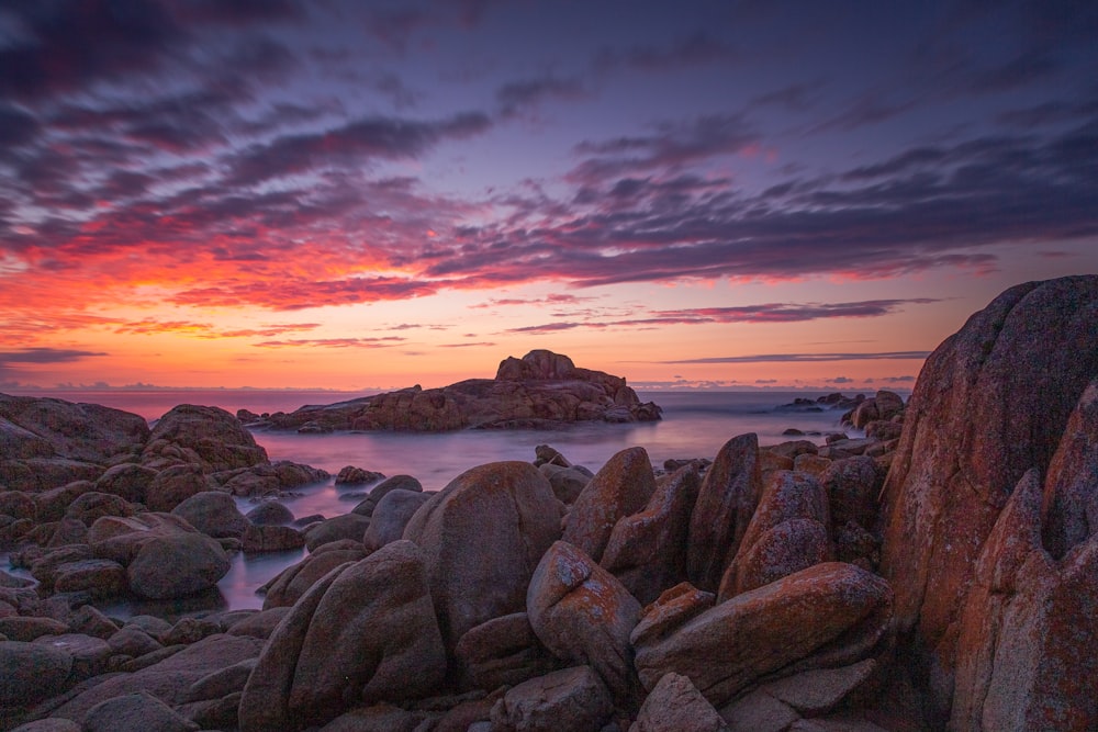 brown rocks on seashore during sunset