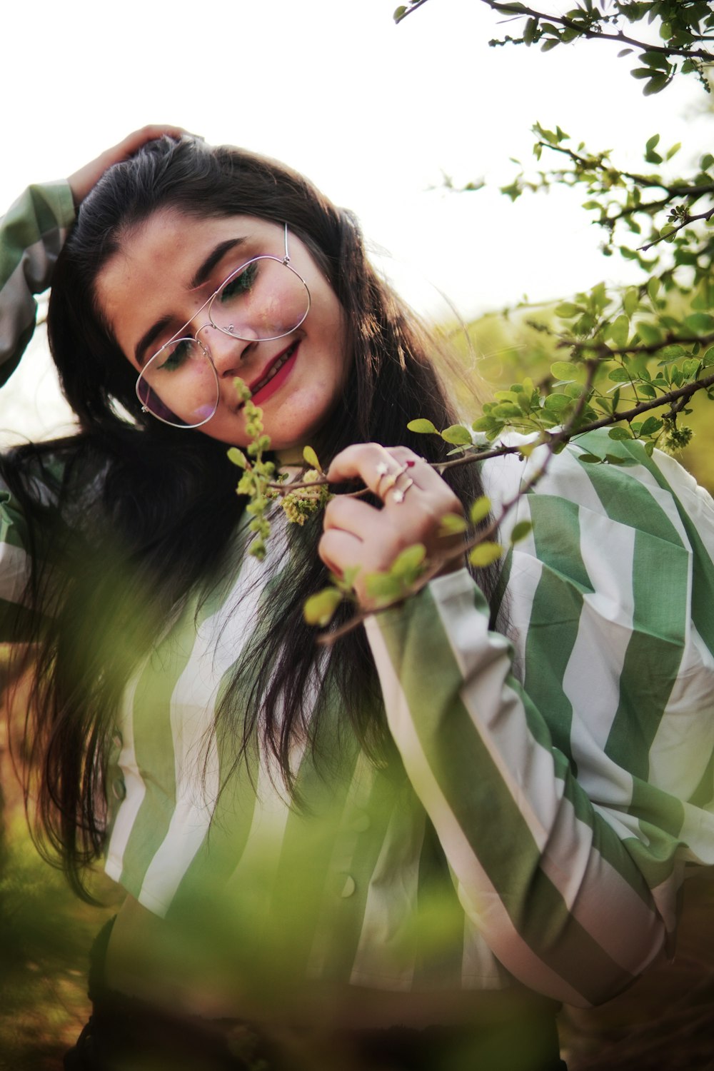 woman in green and white stripe long sleeve shirt holding yellow flower