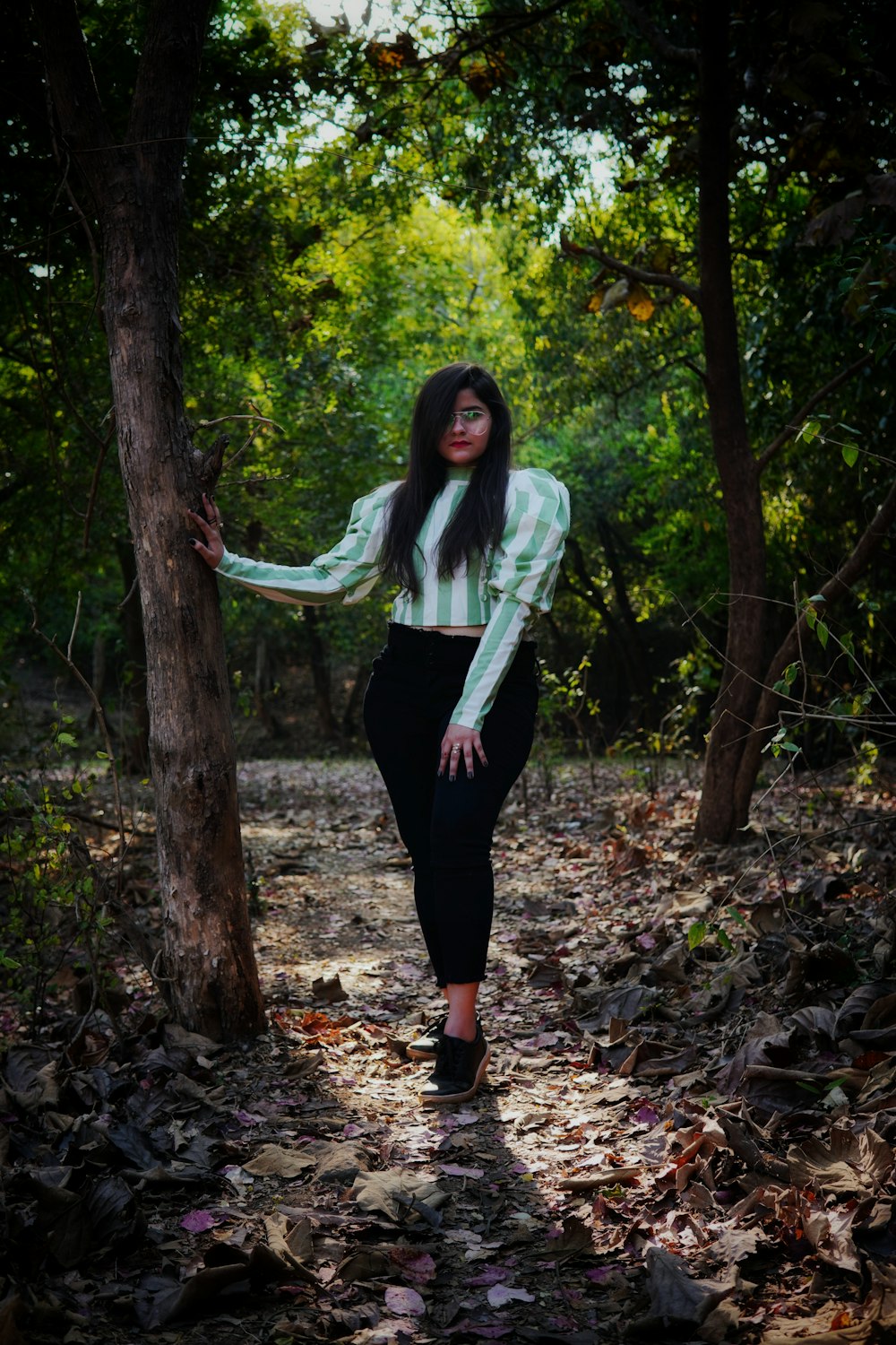 woman in white long sleeve shirt and black pants standing beside tree