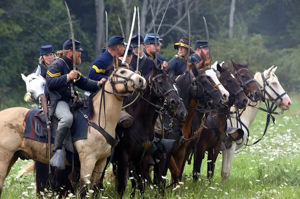 hommes à cheval sur un champ d’herbe verte pendant la journée