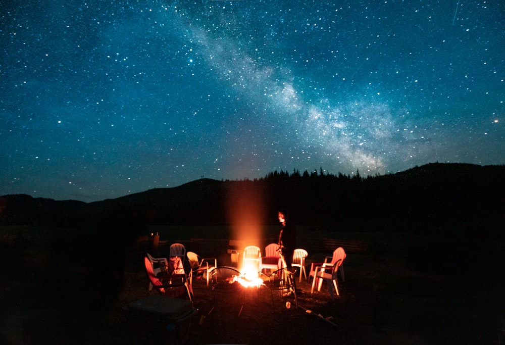 people sitting on camping chairs under starry night