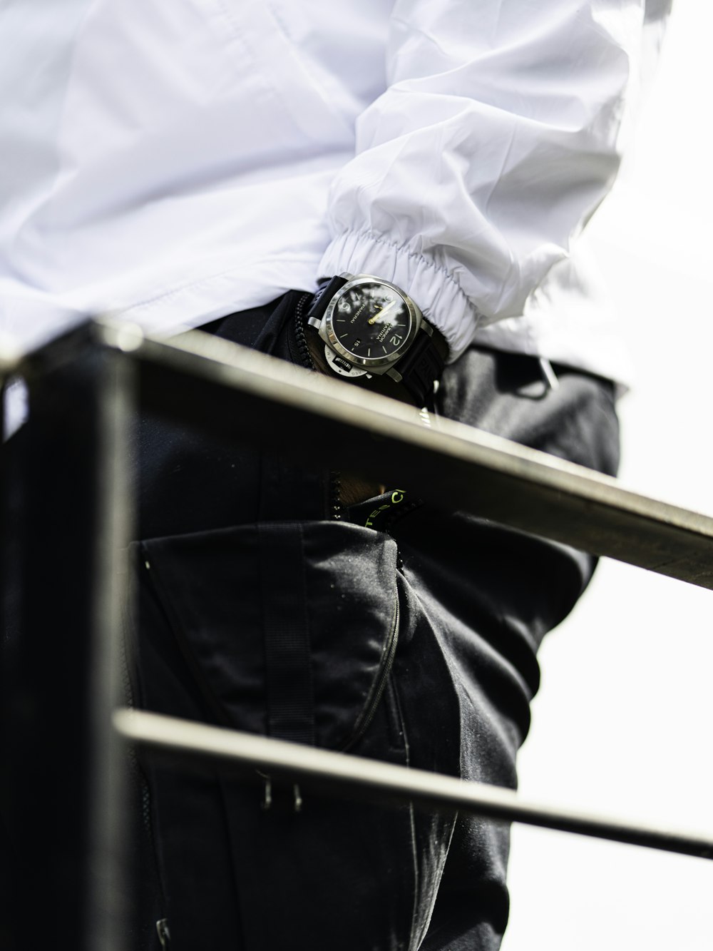 person in white dress shirt and black pants wearing black leather strap round analog watch