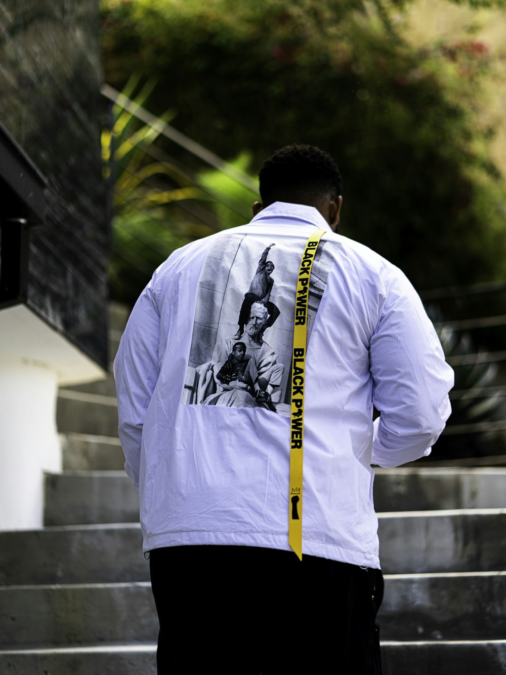 man in white dress shirt and black pants standing near white concrete building during daytime