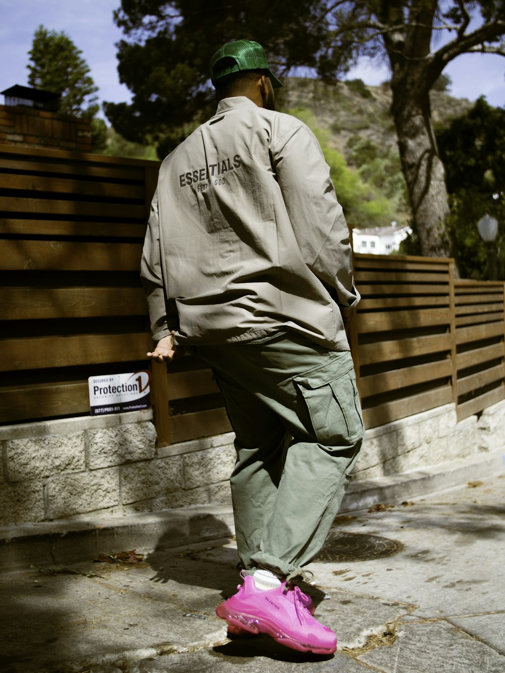 man in brown dress shirt and green pants holding brown wooden crate