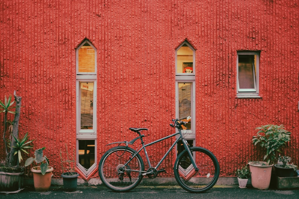 black and white bicycle parked beside red concrete building