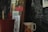 A collection of books stands against a chalkboard with various chalk drawings. A red plant pot with a wooden label marked 'Rucos' and a ceramic mug decorated with colorful flowers are positioned nearby. One of the visible books is by Gabriel Garcia Marquez.